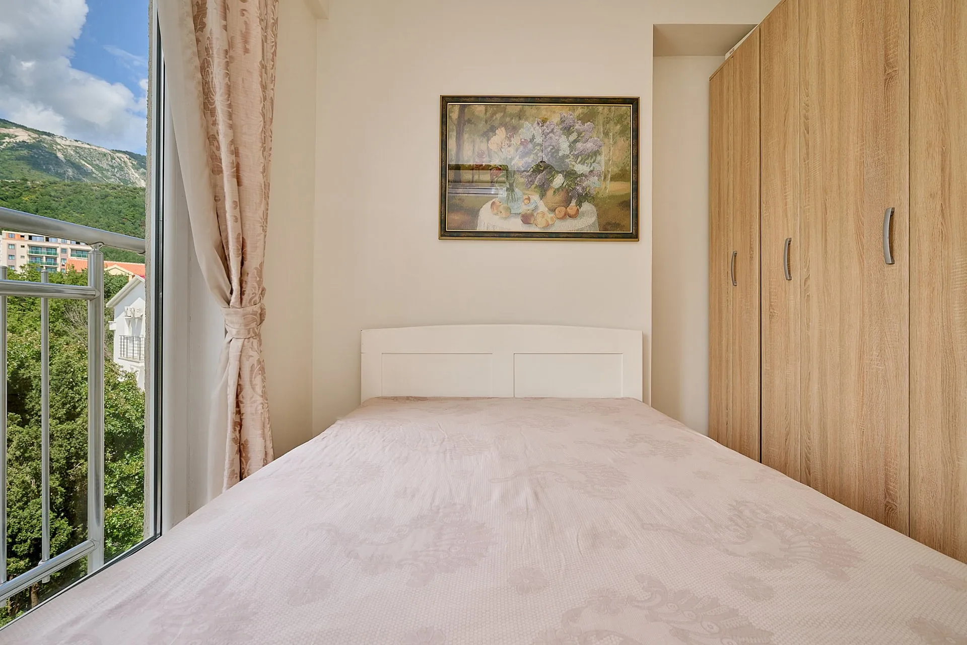 Schlafzimmer in einer Wohnung in Bečići, Montenegro: Doppelbett, Einbauschrank und Bergblick durch das Panoramafenster.