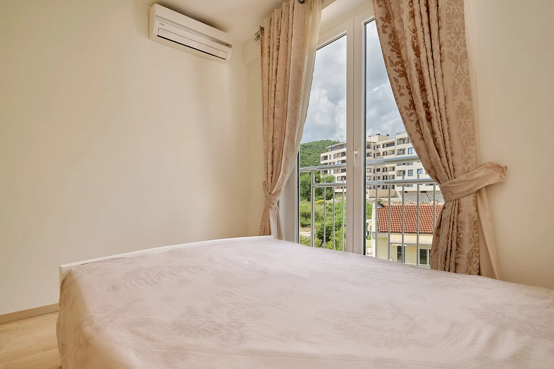 Schlafzimmer in einer Wohnung in Bečići, Montenegro: Doppelbett, Klimaanlage und Zugang zum Balkon mit Bergblick.