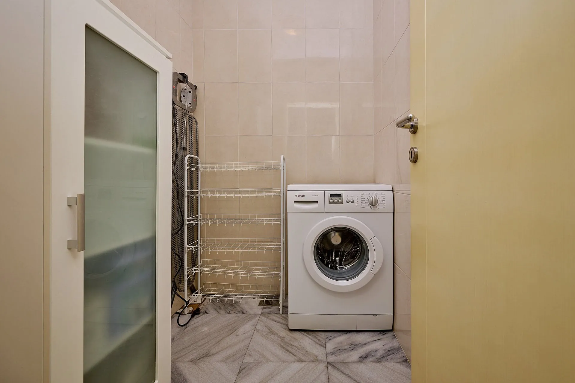 Hauswirtschaftsraum mit weißer Bosch-Waschmaschine und Regal in der Wohnung, Bečići, Montenegro.