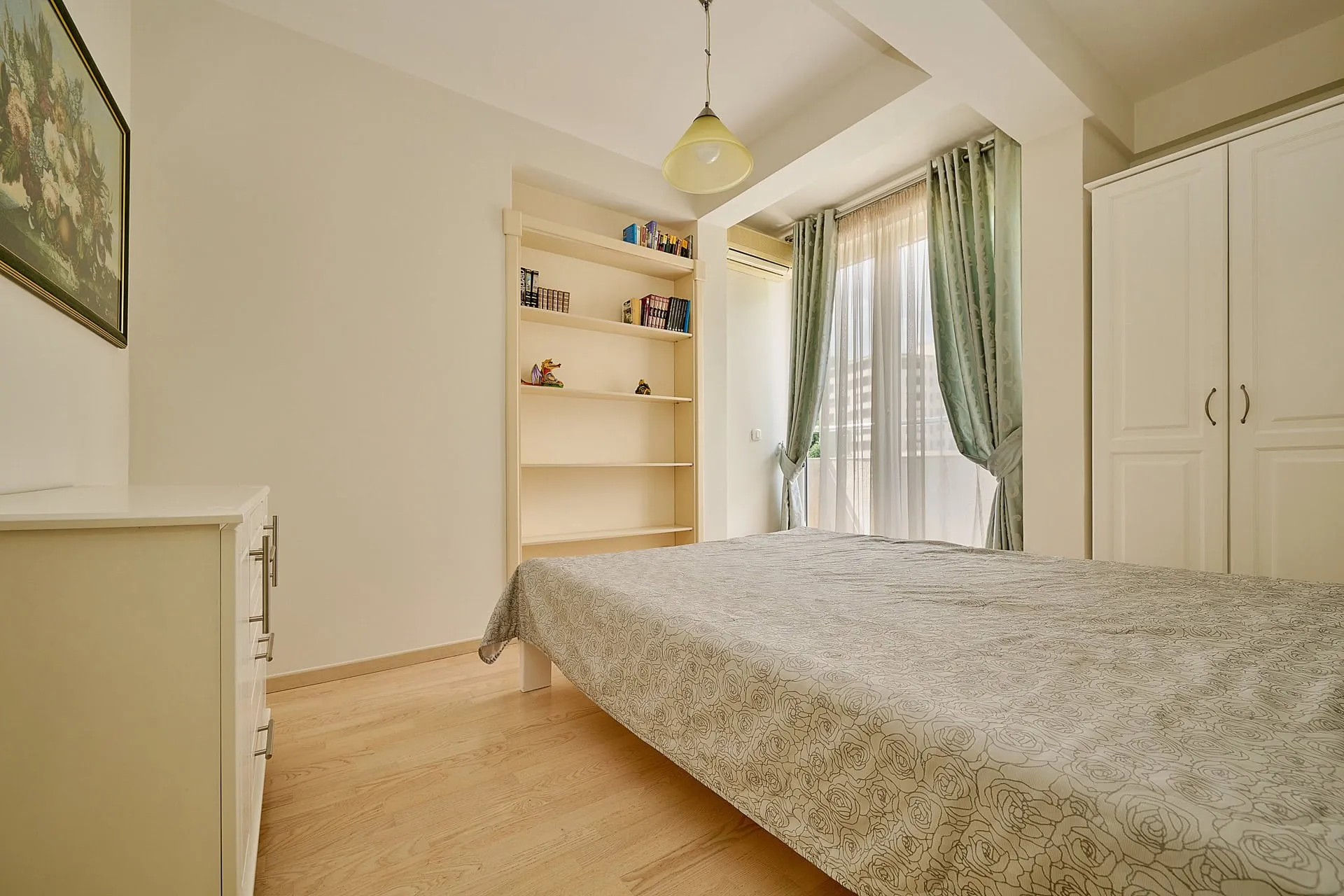 Helles Schlafzimmer mit Doppelbett, Kleiderschrank und Bücherregal in einer Wohnung in Bečići, Montenegro.
