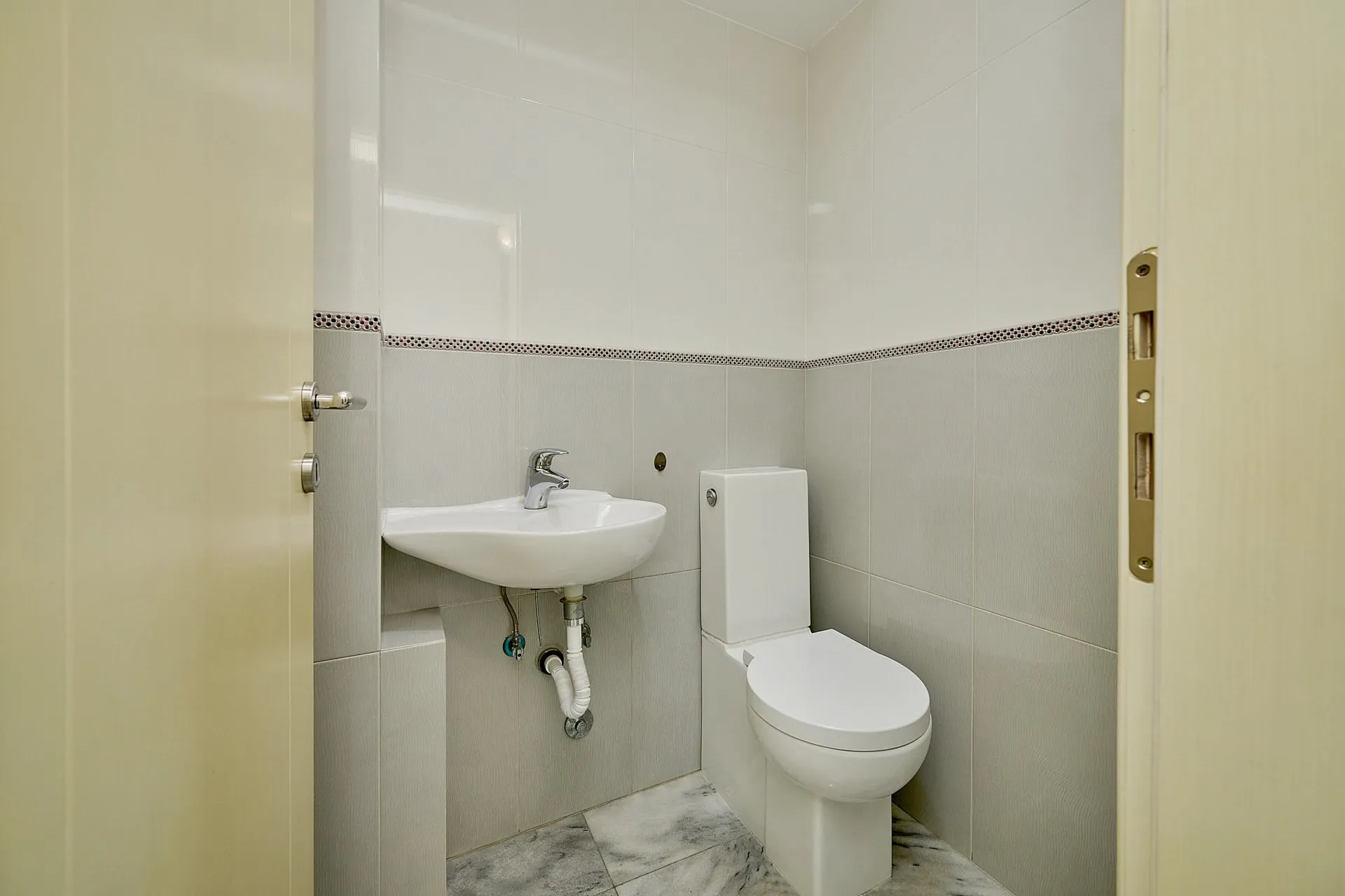 Helles Badezimmer mit weißer Sanitärkeramik und Fliesen in einer Wohnung in Bečići, Montenegro.
