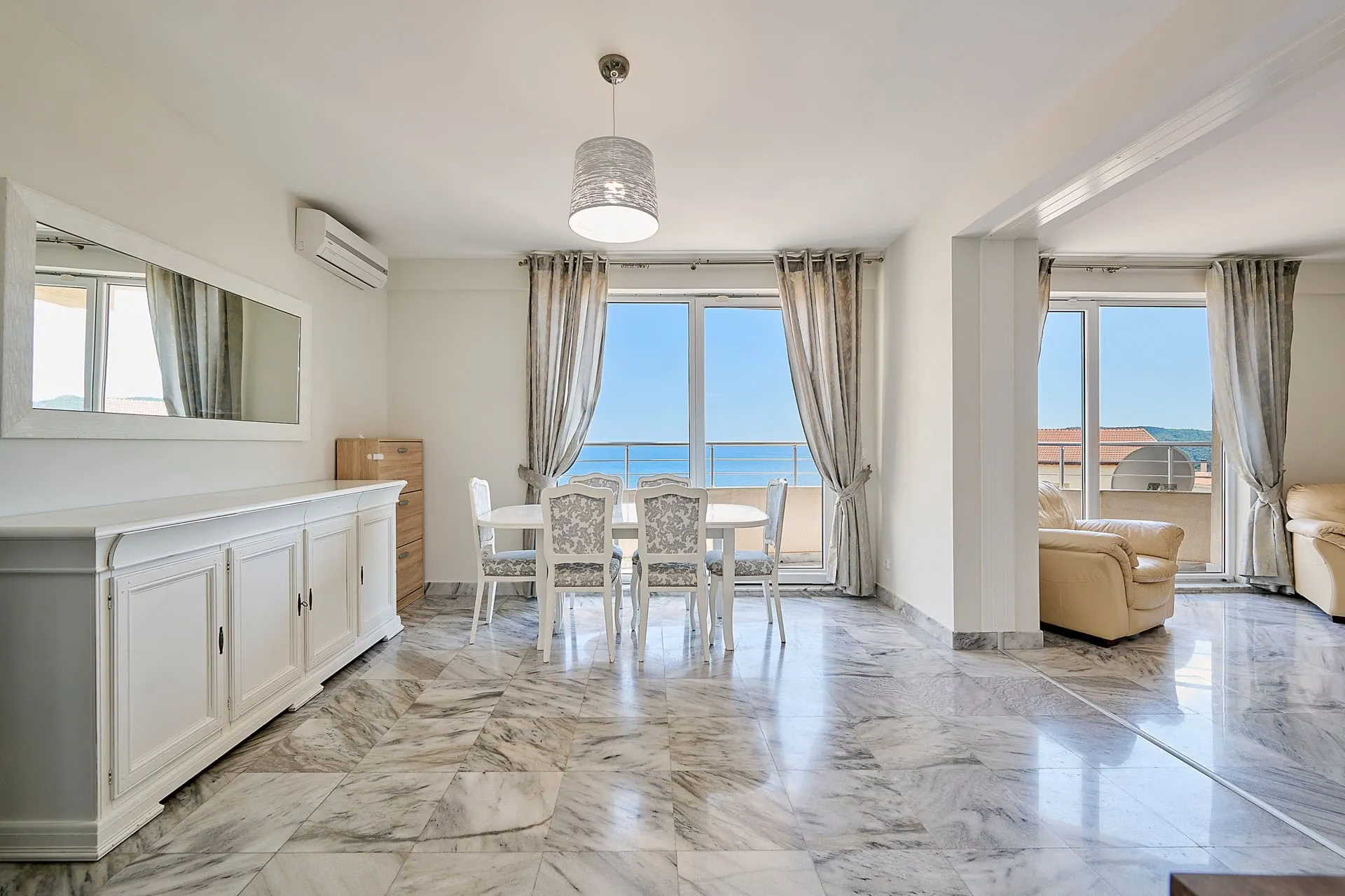 Wohnzimmer mit Marmorboden, Essbereich und Panoramablick auf das Meer in einer Wohnung, Bečići, Montenegro.