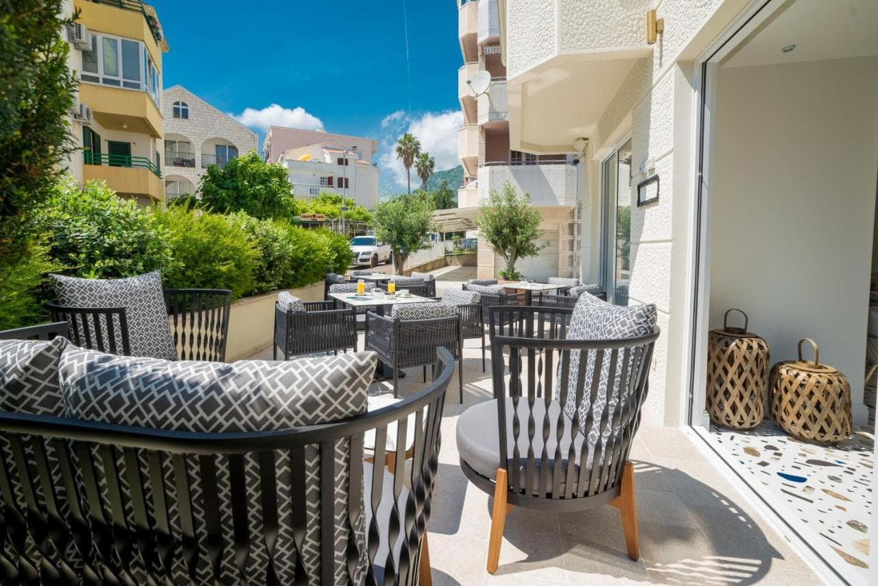 Gemütliche Terrasse mit Rattanmöbeln in einem Hotel in Budva, Montenegro: Blick auf die Stadt, modernes Design und Ruhebereich.
