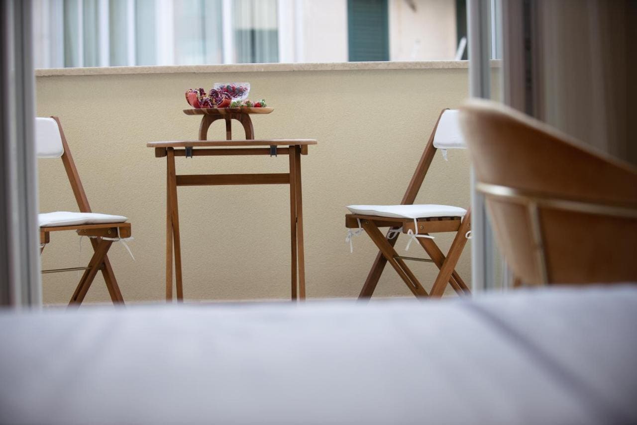 Gemütlicher Balkon mit Holztisch und Stühlen im Hotel in Budva, Montenegro, Blick vom Zimmer auf die Terrasse.