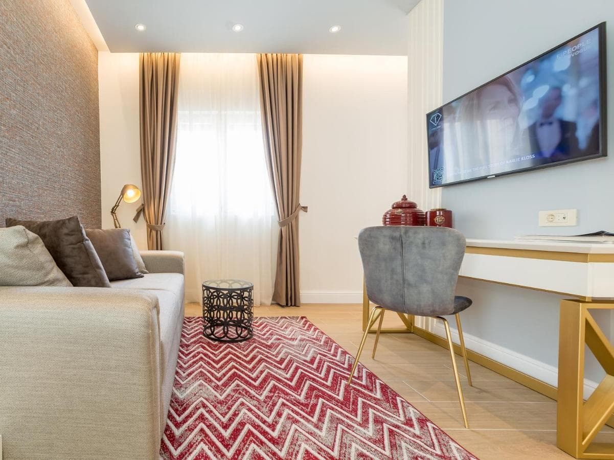 Gemütliches Wohnzimmer in einem Hotel in Budva, Montenegro: moderne Möbel, TV, Teppich mit Zickzackmuster und stilvolle Dekoration.