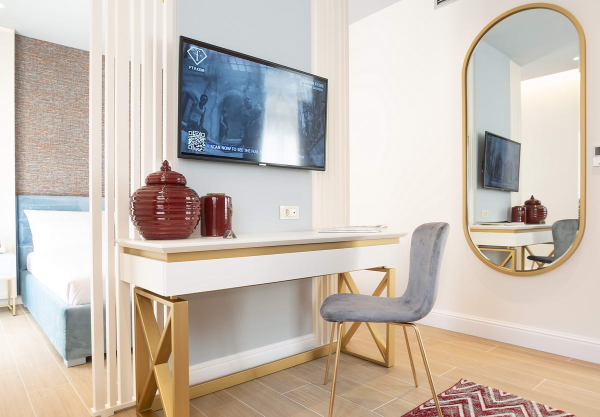 Modernes Schlafzimmer in einem Hotel in Budva, Montenegro: Schreibtisch, TV, großer Spiegel und stilvolles Interieur in hellen Tönen.