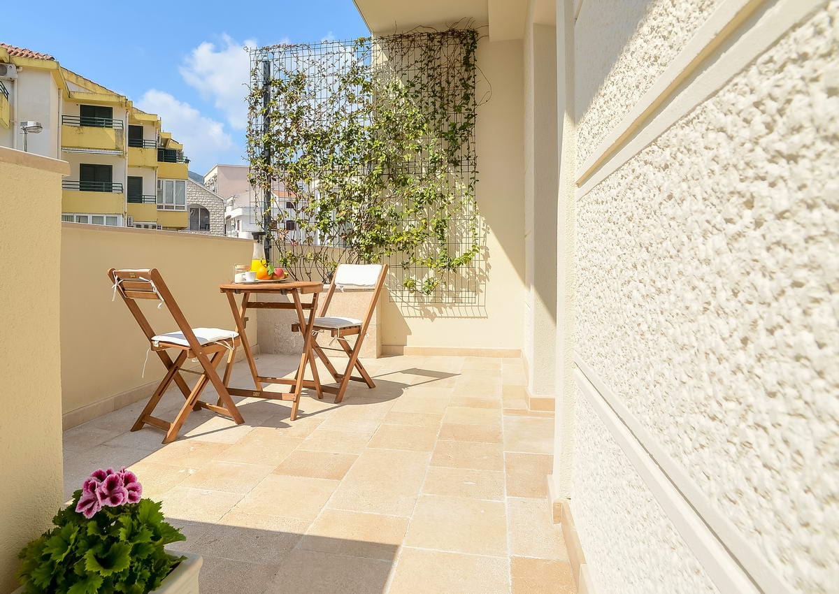 Gemütlicher Balkon mit Holzmöbeln und Kletterpflanzen im Hotel, Budva, Montenegro.