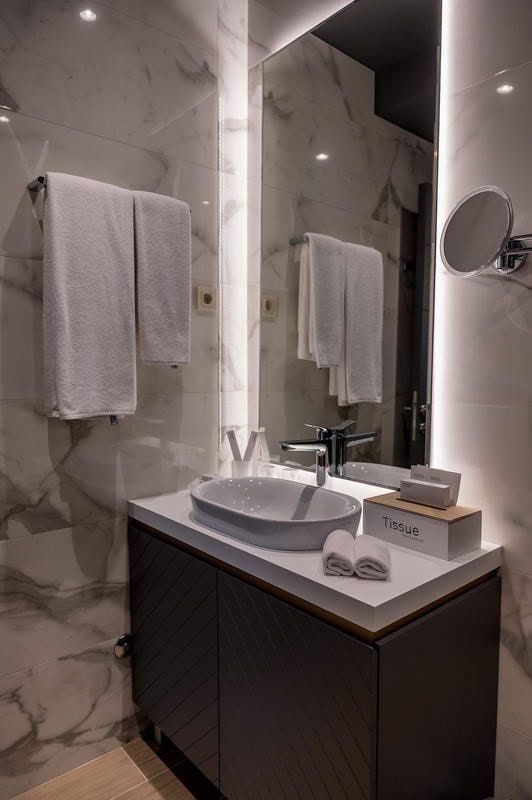 Modernes Badezimmer mit Marmorverkleidung und Beleuchtung im Hotel in Budva, Montenegro.