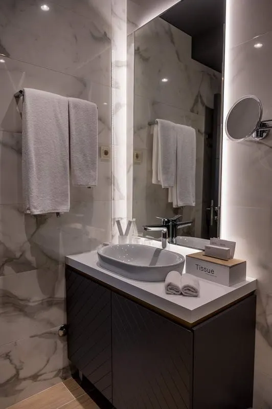 Modernes Badezimmer mit Marmorverkleidung und Beleuchtung im Hotel in Budva, Montenegro.