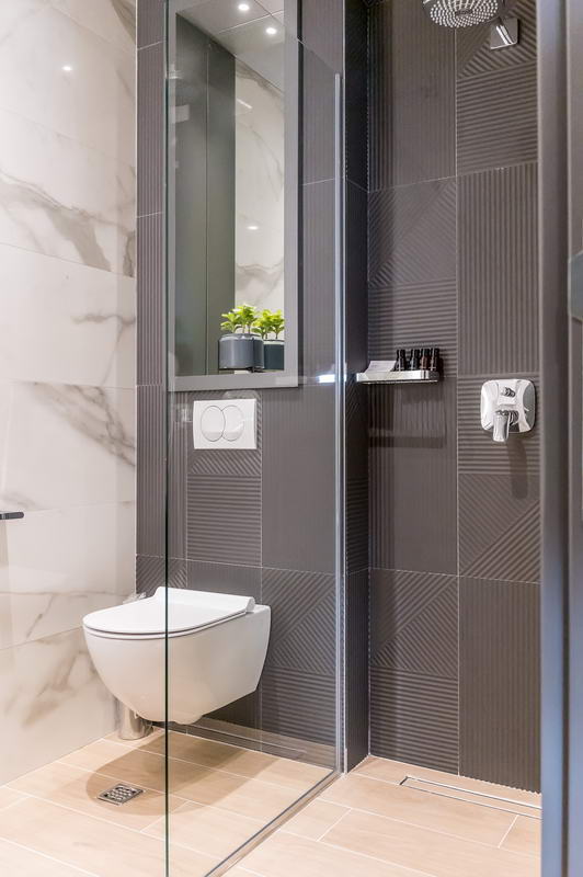 Modernes Badezimmer in einem Hotel in Budva, Montenegro: Duschkabine, wandhängendes WC und Marmoroptik-Fliesen.