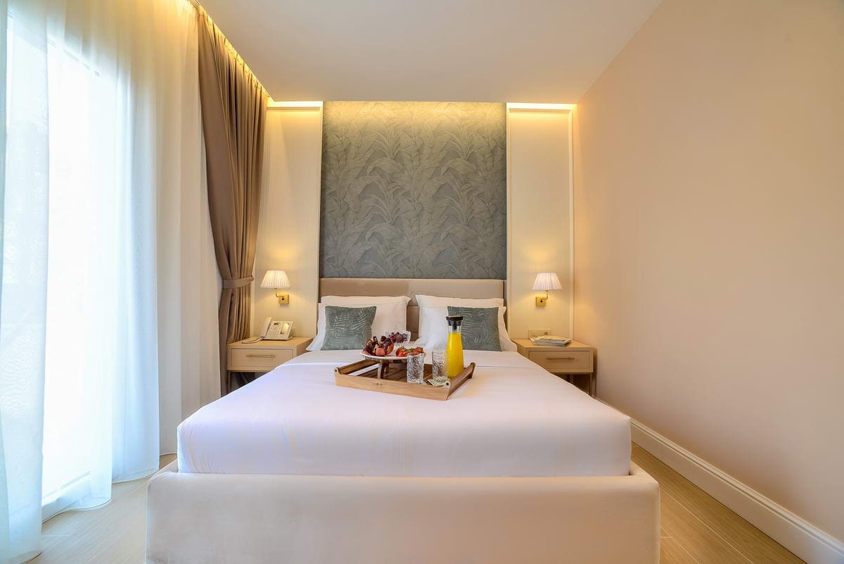 Modernes Schlafzimmer mit Doppelbett in einem Hotel in Budva, Montenegro: stilvolles Interieur, Beleuchtung und Frühstück aufs Zimmer.