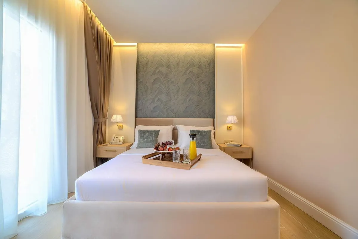 Modernes Schlafzimmer mit Doppelbett in einem Hotel in Budva, Montenegro: stilvolles Interieur, Beleuchtung und Frühstück aufs Zimmer.