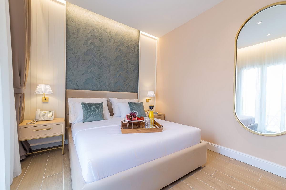 Modernes Schlafzimmer in einem Hotel in Budva, Montenegro: Doppelbett, Designspiegel und stilvolle Wandverkleidung.