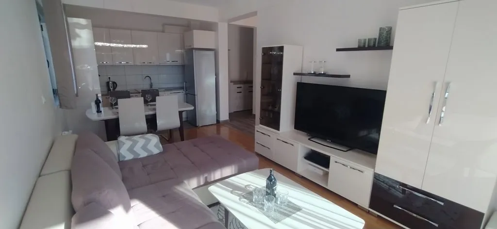 Modernes Wohnzimmer mit Küche in einer Wohnung in Bečići, Montenegro: Ecksofa, Hochglanzmöbel und Essbereich.