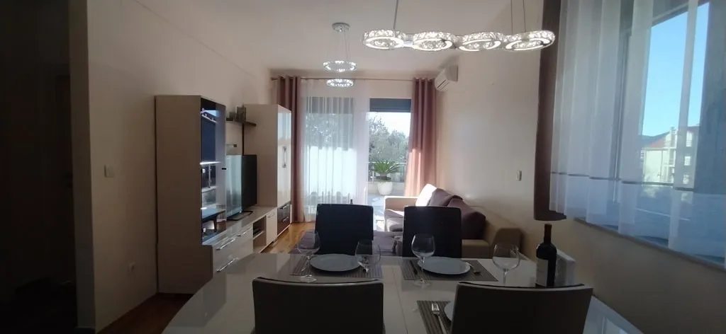 Wohnzimmer mit Essbereich in einer Wohnung in Bečići, Montenegro: moderne Möbel, helles Interieur und Zugang zur Terrasse.