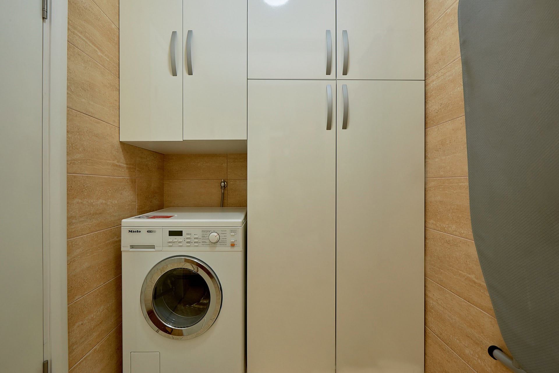 Badezimmer mit weißem Schrank und Waschmaschine in einer Wohnung in Bečići, Montenegro