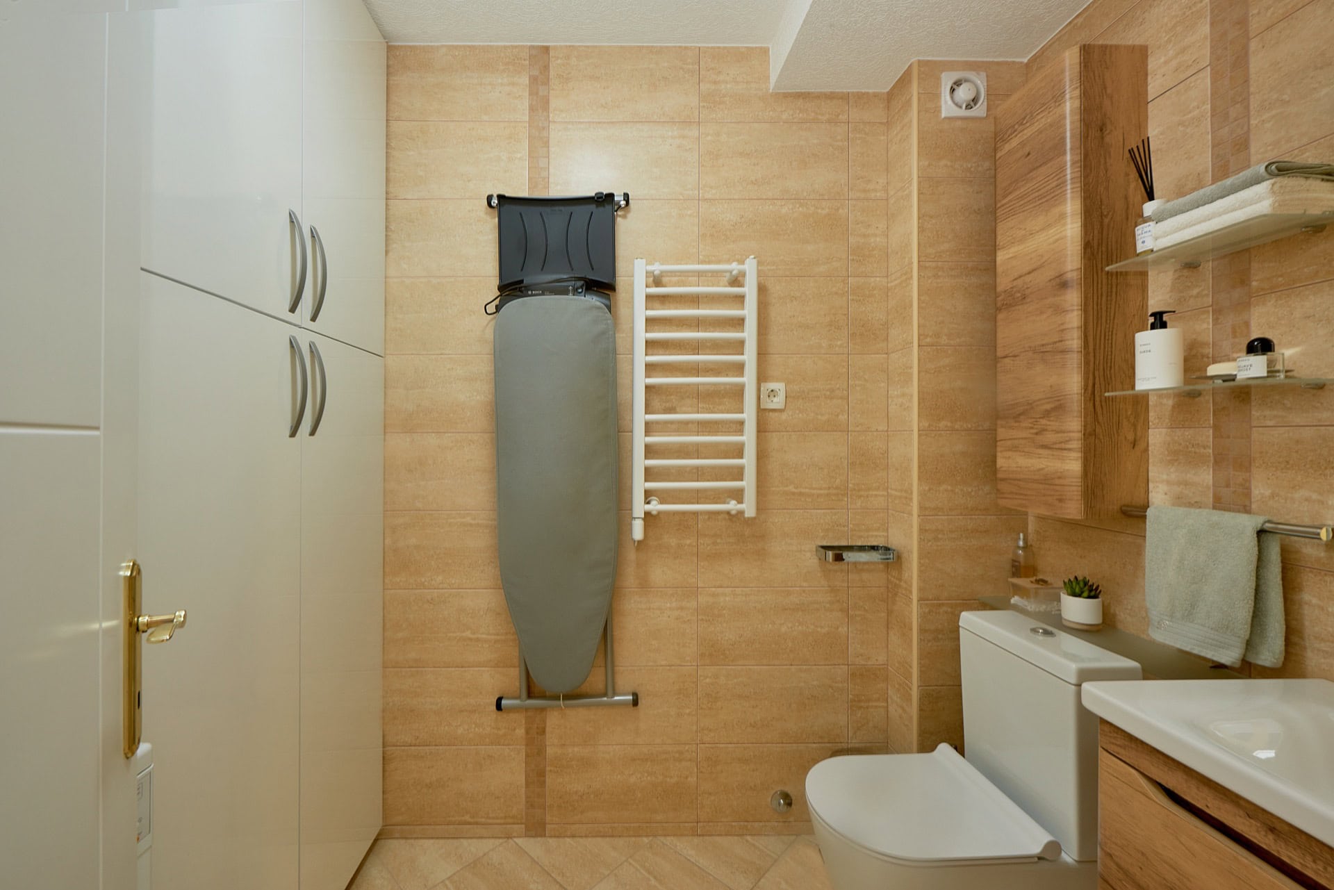 Modernes Badezimmer mit weißer Sanitärkeramik, beigen Fliesen und einem Schrank in einer Wohnung in Bečići, Montenegro.