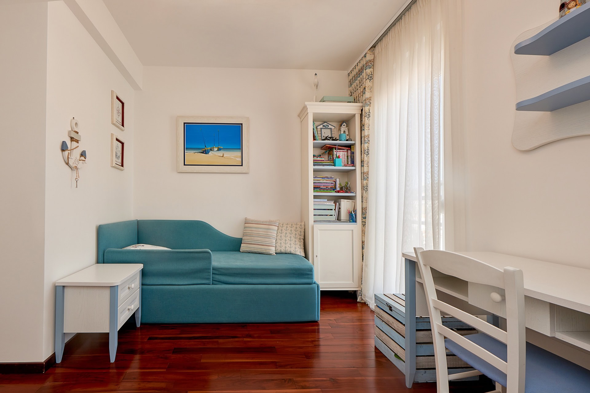 Kinderzimmer im maritimen Stil mit blauem Sofa, Schreibtisch und weißen Möbeln im Penthouse in Bečići, Montenegro