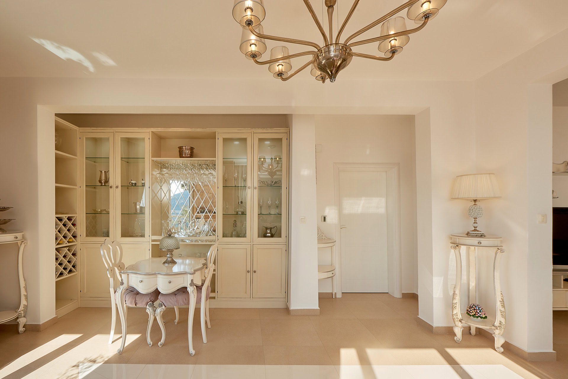 Helle Wohnzimmer mit weißer klassischer Möblierung, Geschirrvitrine und Essbereich im Penthouse in Bečići, Montenegro
