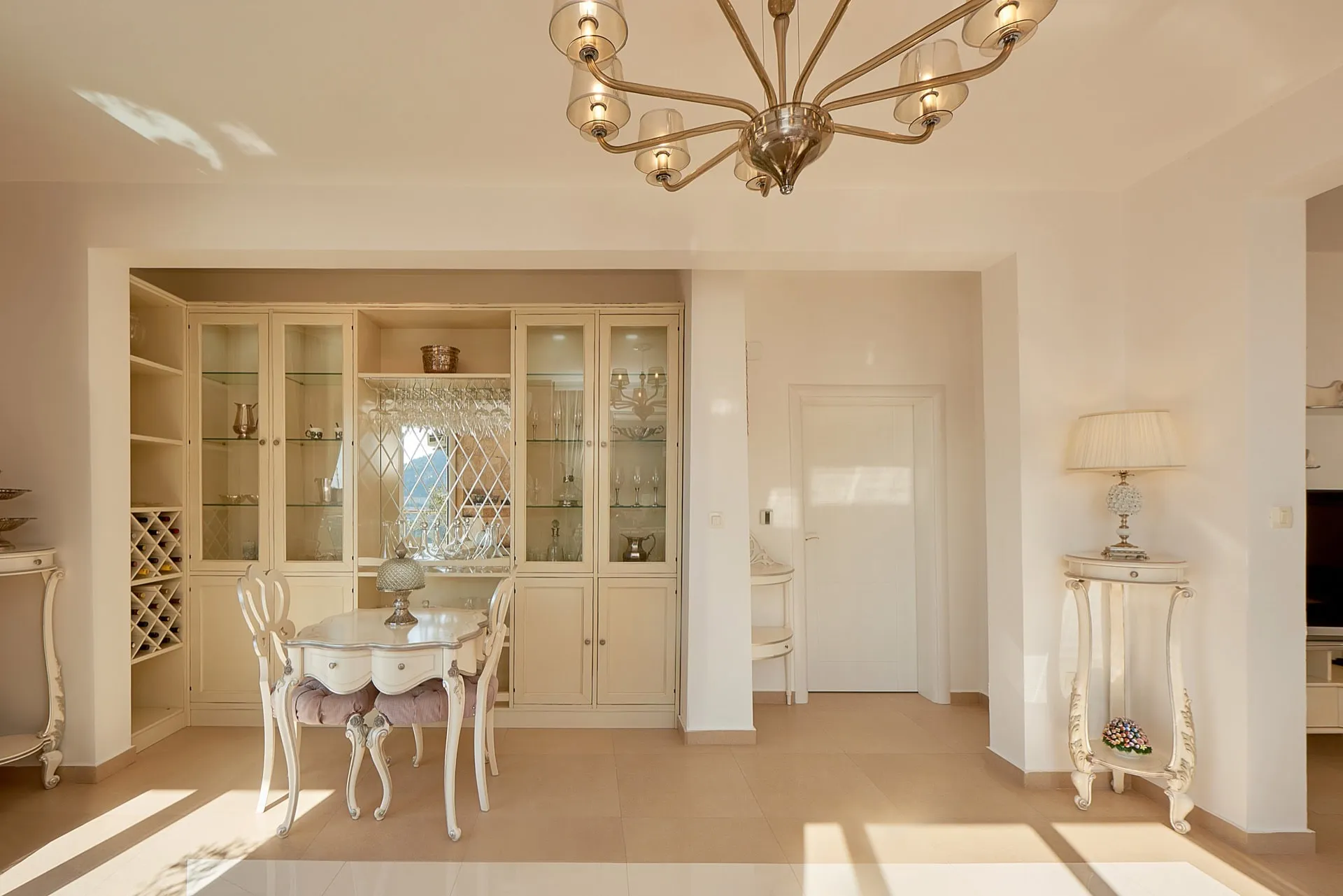 Helle Wohnzimmer mit weißer klassischer Möblierung, Geschirrvitrine und Essbereich im Penthouse in Bečići, Montenegro