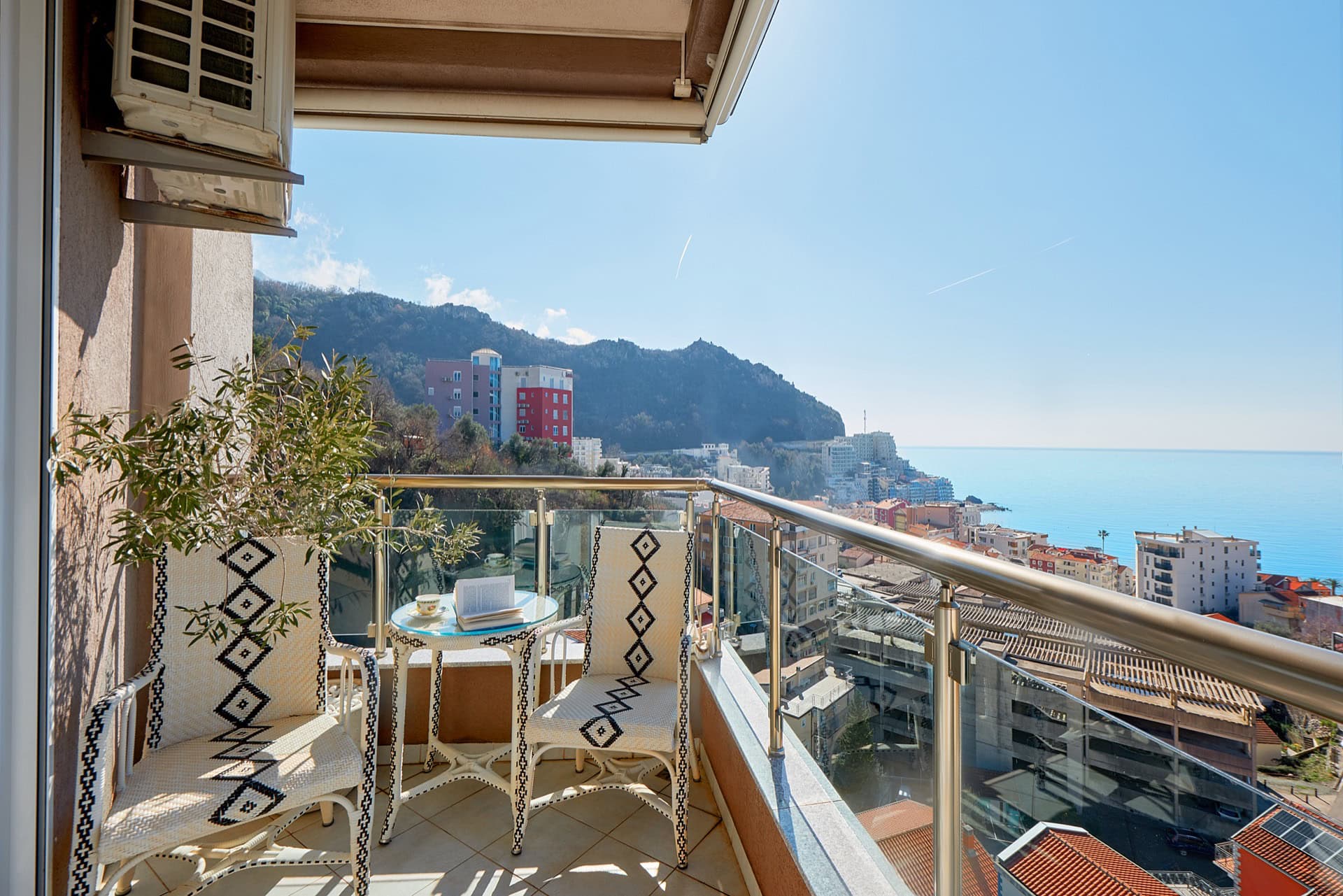 Möblierter Balkon mit Korbstühlen, Tisch und Panoramablick auf das Meer und die Berge in Bečići, Montenegro