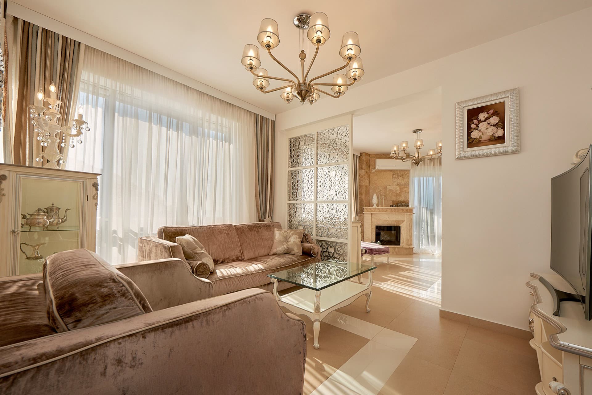 Geräumiges Wohnzimmer mit beigen Sofas, Kamin und Panoramafenstern im Penthouse, Bečići, Montenegro