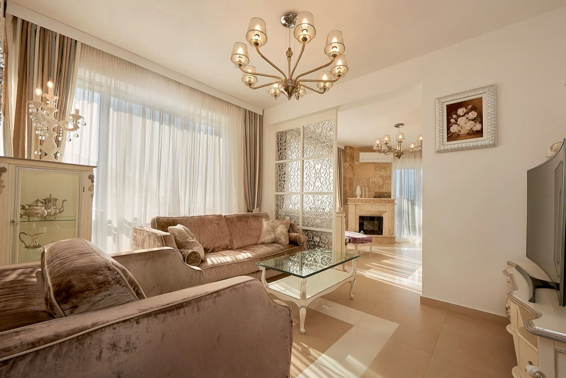 Geräumiges Wohnzimmer mit beigen Sofas, Kamin und Panoramafenstern im Penthouse, Bečići, Montenegro