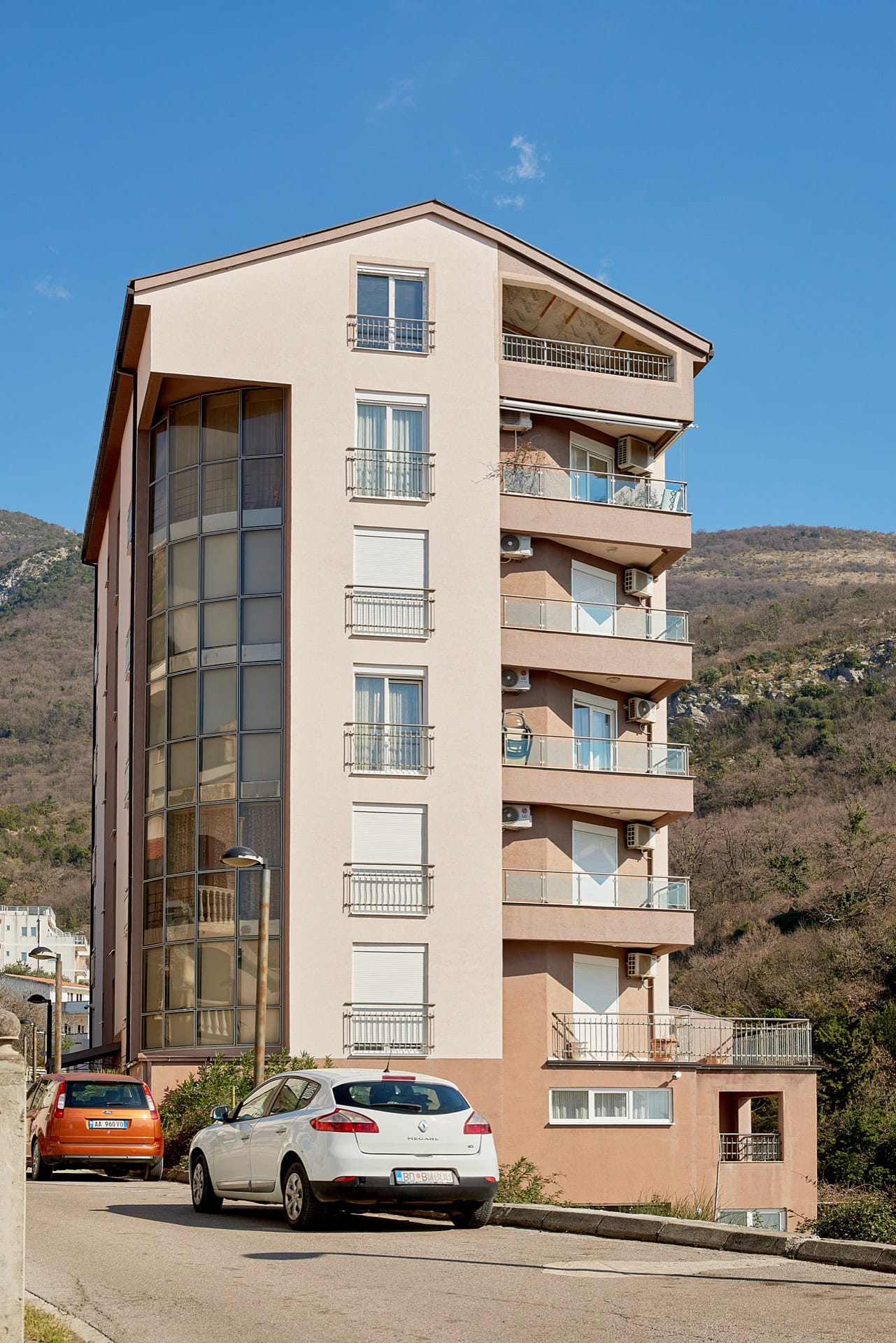 Modernes Mehrfamilienhaus mit Panoramabalkonen und Bergen im Hintergrund in Bečići, Montenegro