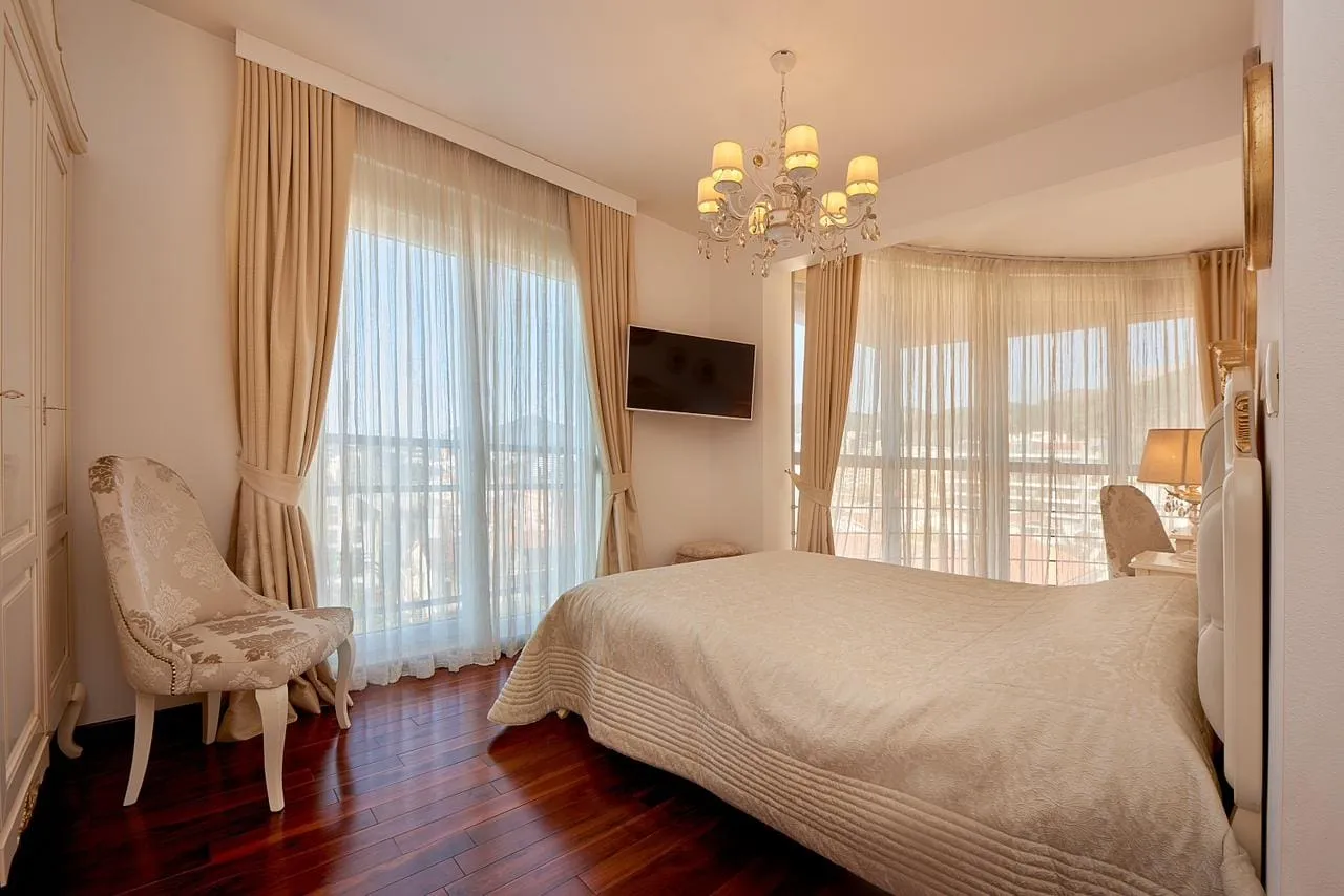 Helle Schlafzimmer mit Panoramafenstern, Doppelbett und Sessel im Penthouse in Bečići, Montenegro