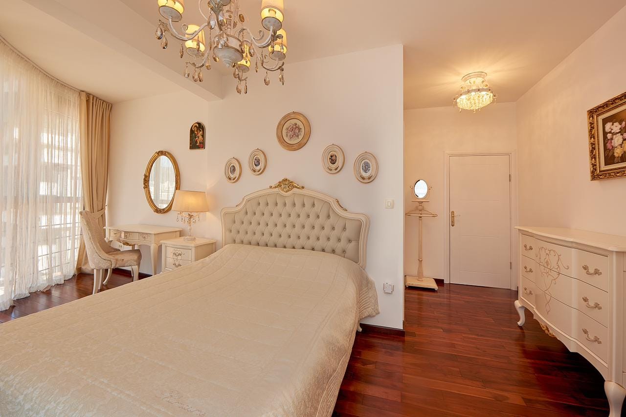 Schlafzimmer im klassischen Stil mit weißen Möbeln und Parkettboden im Penthouse in Bečići, Montenegro