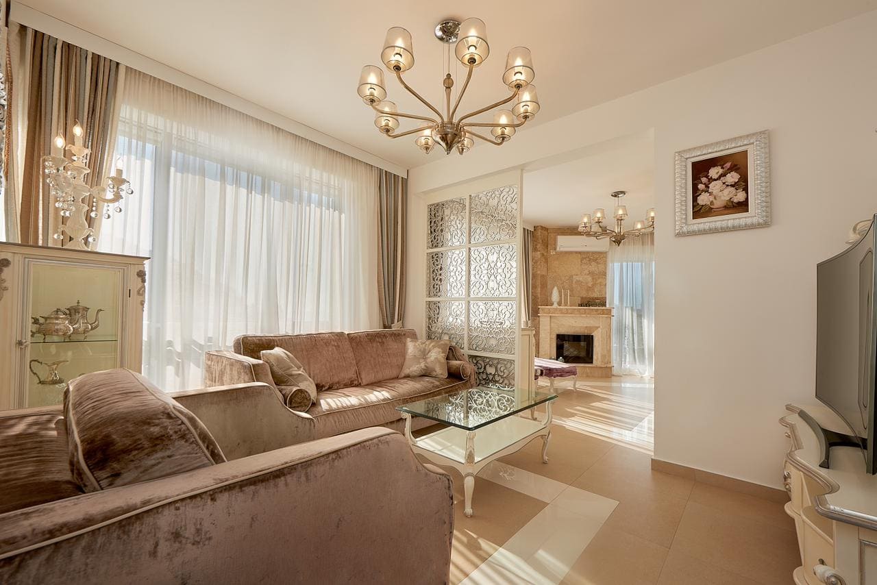 Geräumiges Wohnzimmer mit beigen Sofas, Glastisch und Kronleuchter im Penthouse in Bečići, Montenegro