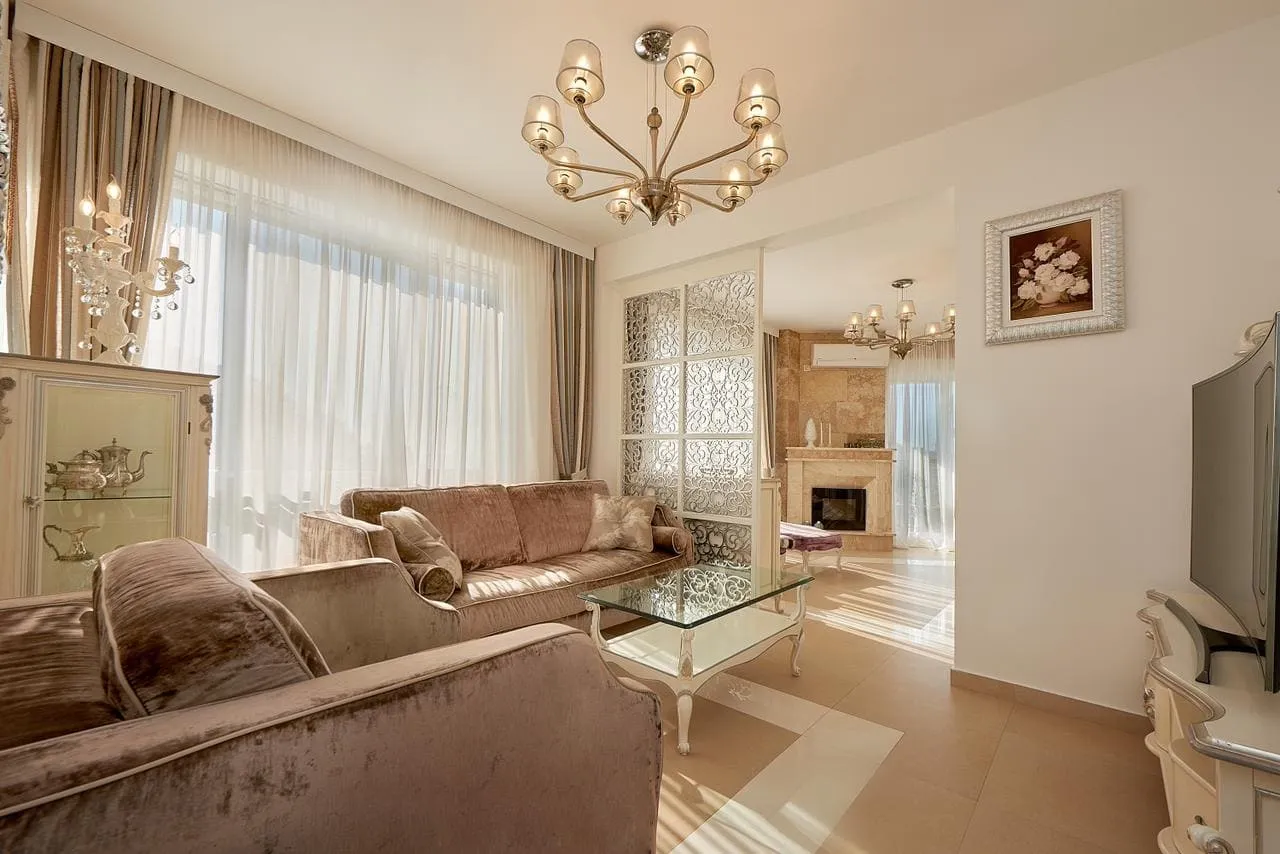 Geräumiges Wohnzimmer mit beigen Sofas, Glastisch und Kronleuchter im Penthouse in Bečići, Montenegro
