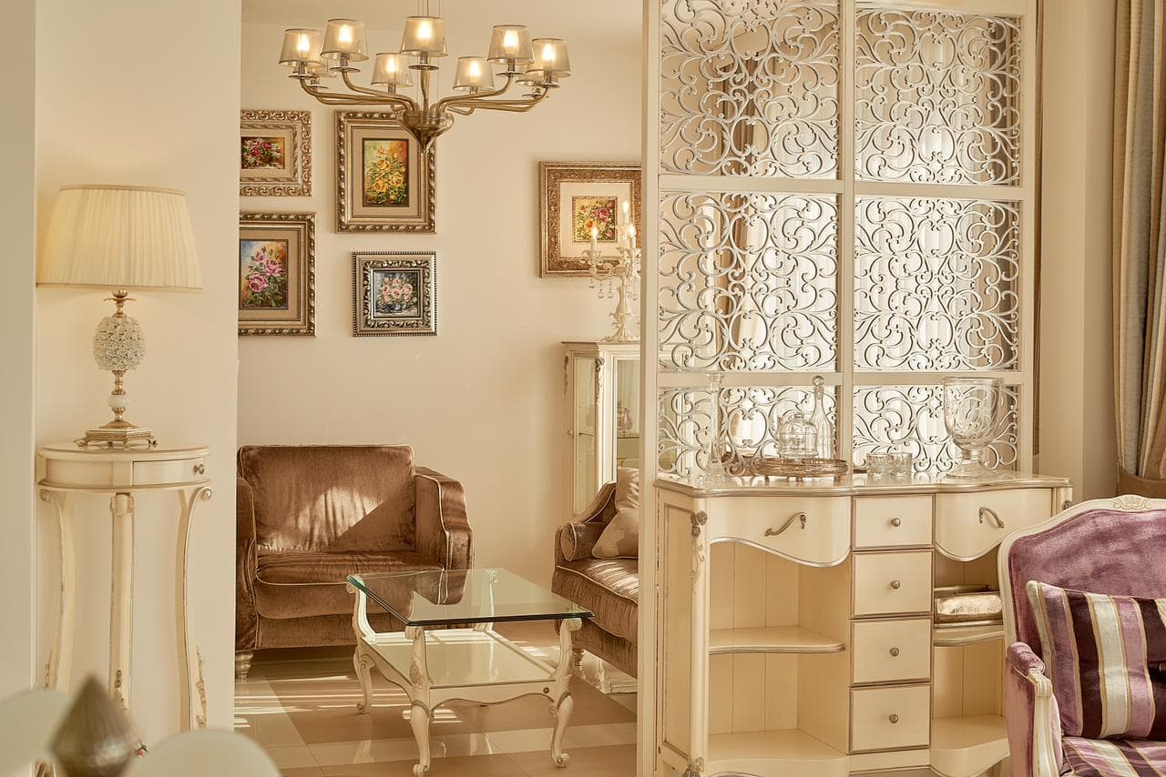 Klassisches Wohnzimmer mit geschnitzter Trennwand, Kommode, Sesseln und Gemälden in einer exklusiven Penthouse-Wohnung in Bečići, Montenegro