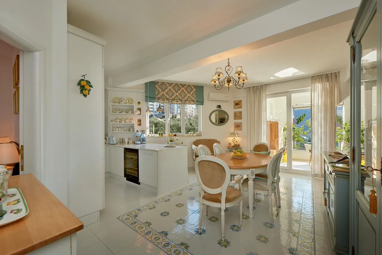 Helle Wohnküche mit Essbereich, weißen Möbeln und gemusterten Fliesen auf dem Boden im Penthouse, Bečići, Montenegro