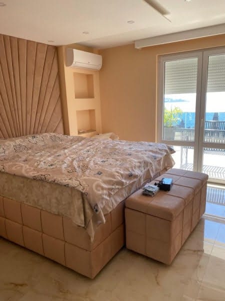 Bedroom with a large bed and sea view in a house, Shushan, Montenegro: beige finishes, soft headboard, and balcony.