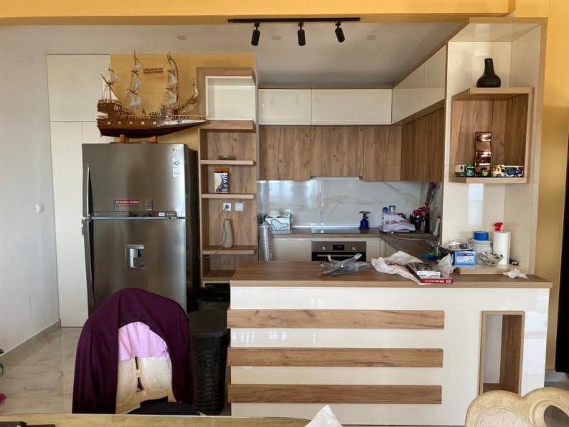 Modern kitchen with a breakfast bar and built-in appliances in a house, Shushan, Montenegro. Bright interior with wood finish.