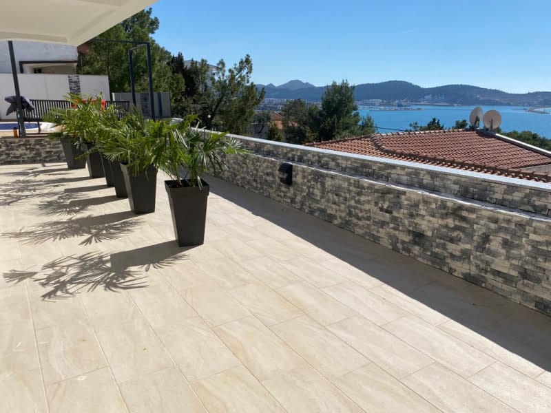 Spacious terrace with sea view in a house, Shushan, Montenegro: stone finish, floor tiles, and palm planters.