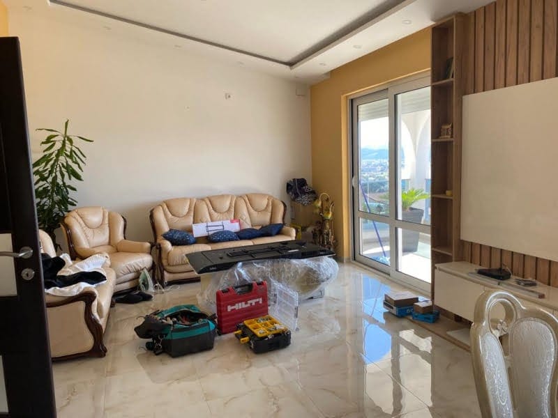 Living room in a house in Shushan, Montenegro: a bright room with leather furniture, a panoramic window, and wood finishes.