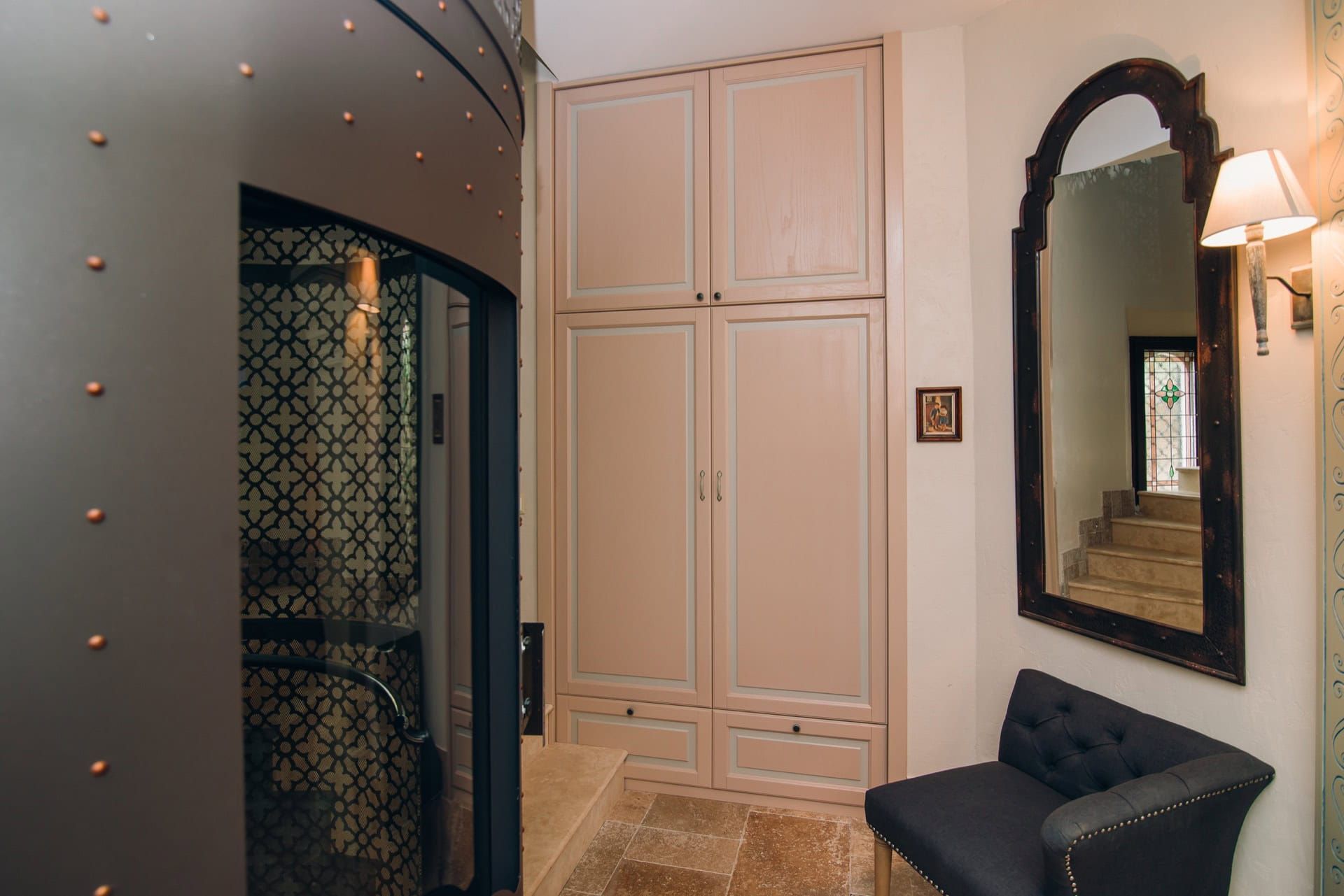 Intérieur de l’entrée d’une villa à Reževići, Monténégro : placard intégré, miroir vintage, fauteuil et finition design.