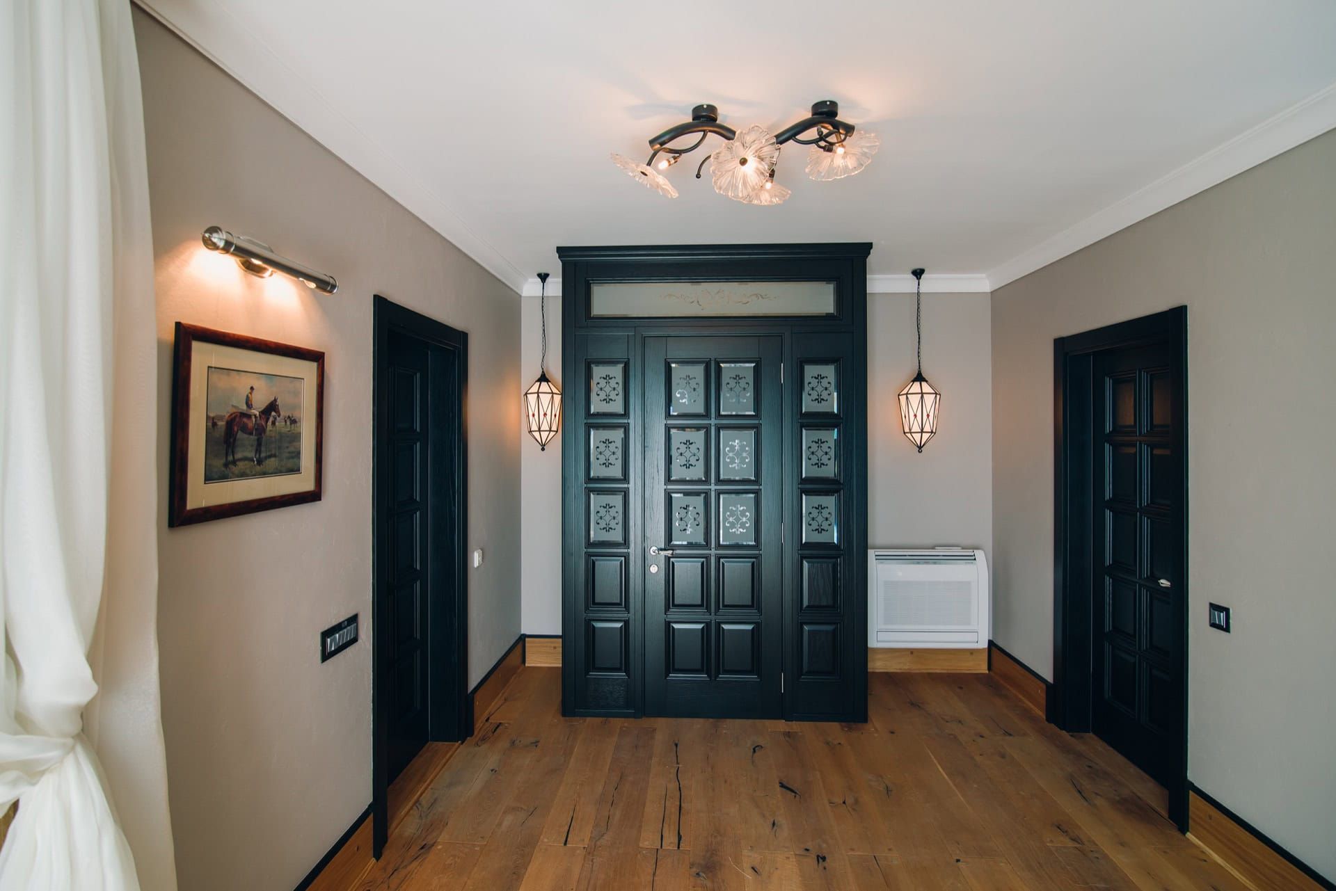 Intérieur de l’entrée d’une villa à Reževići, Monténégro : portes intérieures noires, éclairage design et parquet en bois.