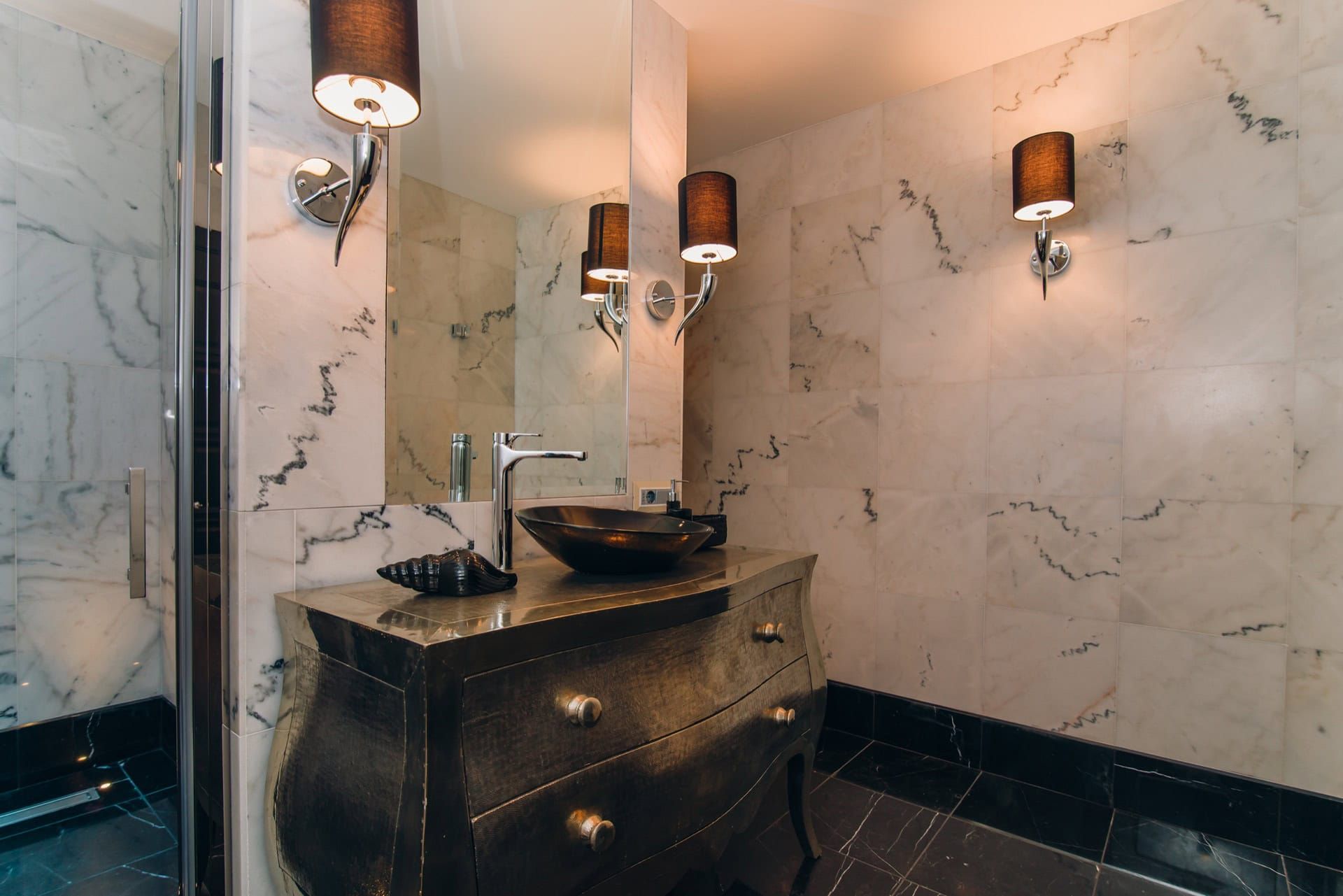 Salle de bains dans une villa à Reževići, Monténégro : finition en marbre, meuble vasque design et éclairage élégant.