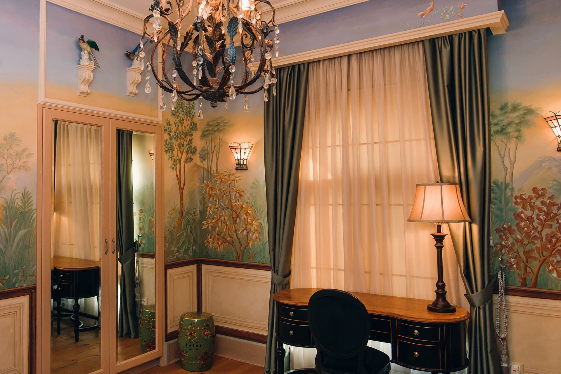 Chambre à coucher dans une villa à Reževići, Monténégro : intérieur classique avec peinture murale artistique, lustre et bureau.