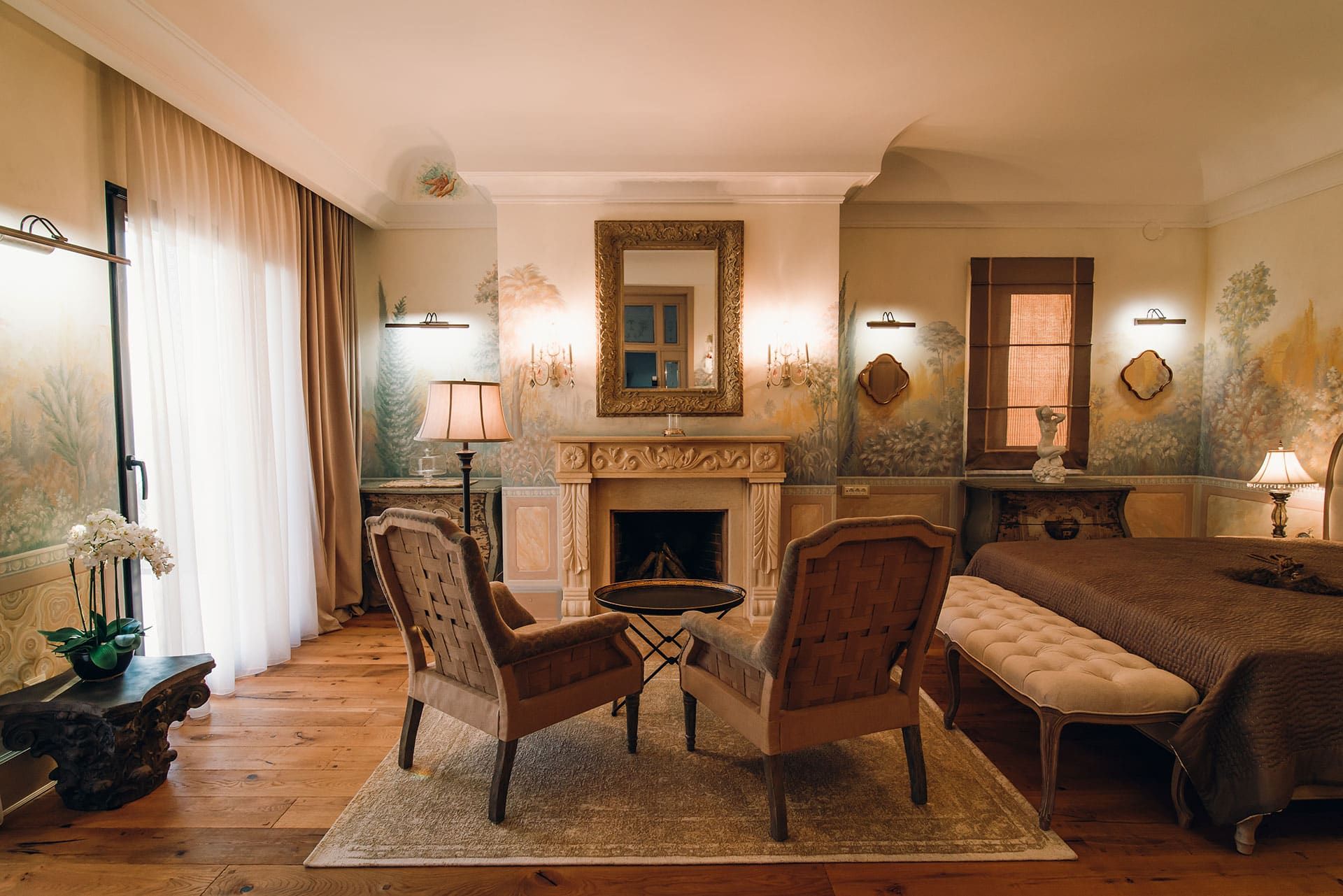Chambre luxueuse avec cheminée et peinture murale artistique dans une villa à Reževići, Monténégro : mobilier et décoration classiques.