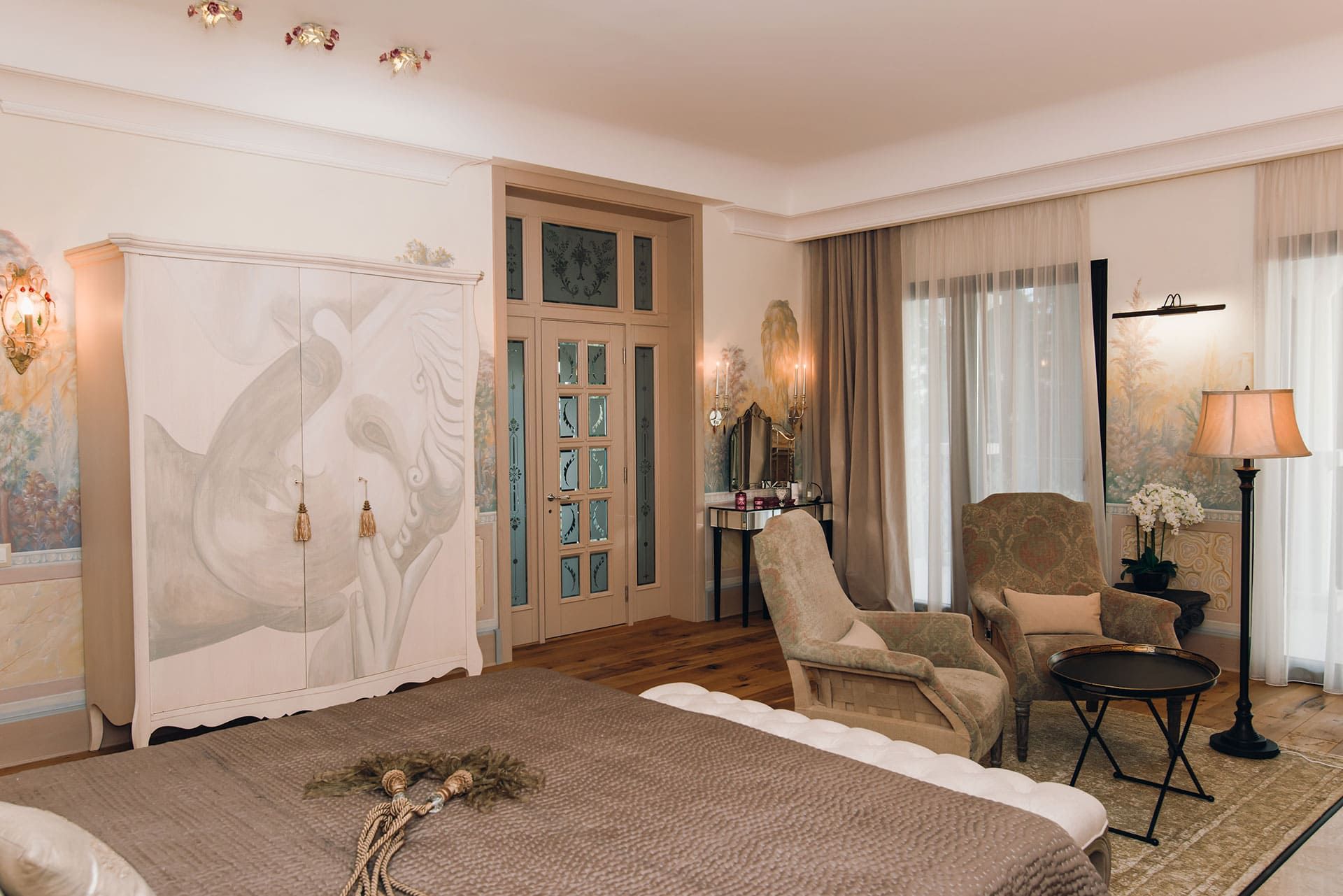 Intérieur de la chambre dans une villa à Reževići, Monténégro : mobilier design, peinture murale et parquet.
