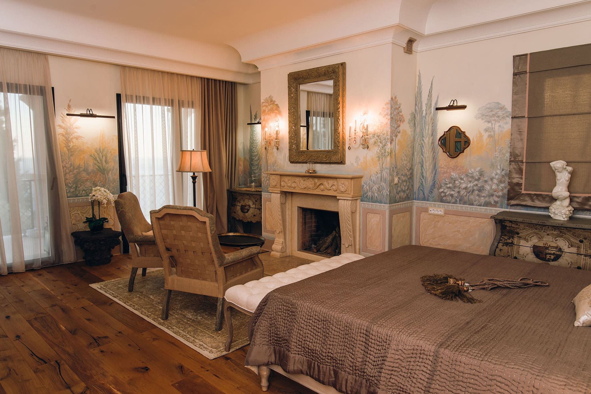 Chambre luxueuse avec cheminée et peinture murale artistique dans une villa à Reževići, Monténégro. Vue sur la mer et la terrasse.