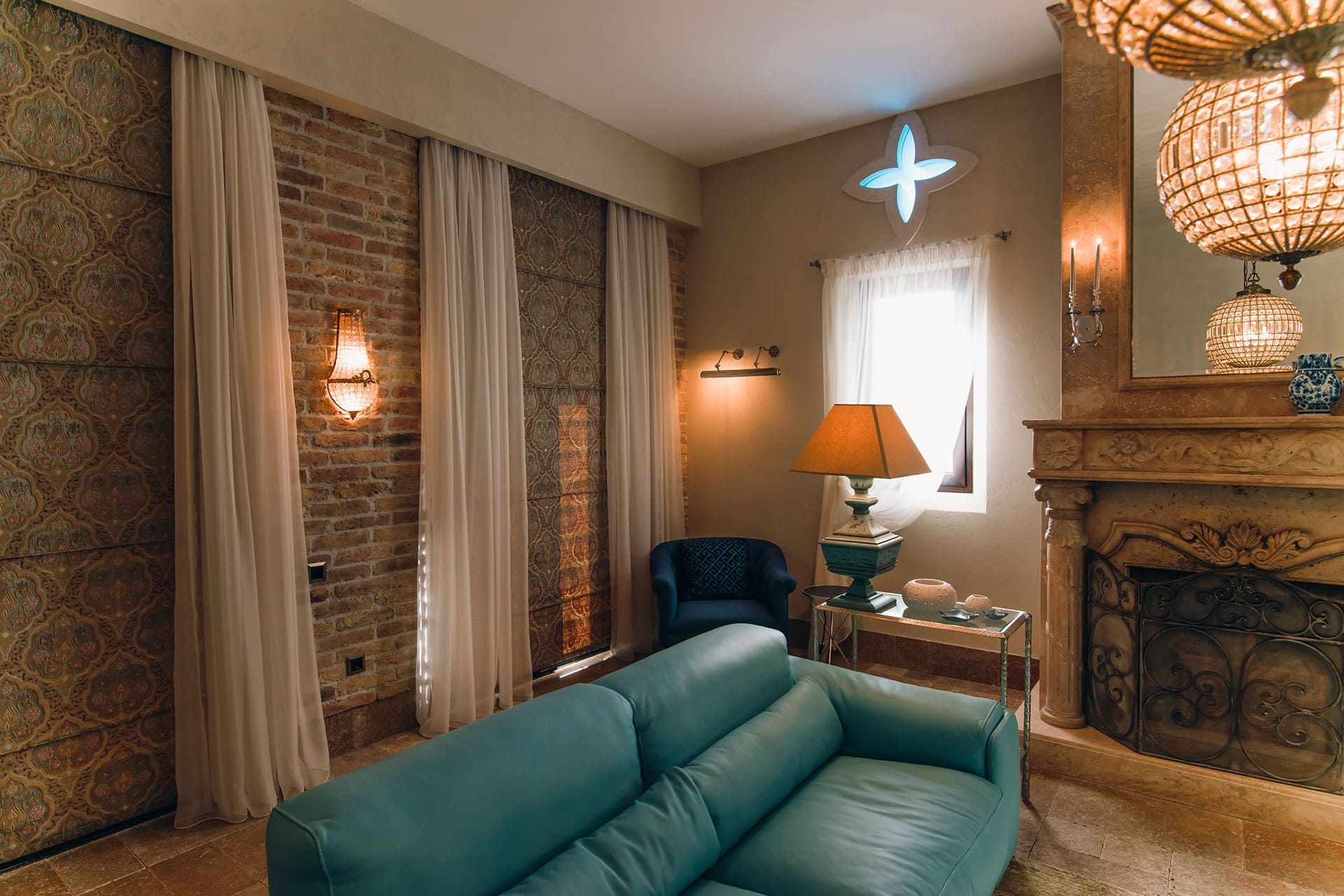 Salon de la villa à Reževići, Monténégro : canapé en cuir, cheminée en pierre, mur en briques et lustres en cristal.