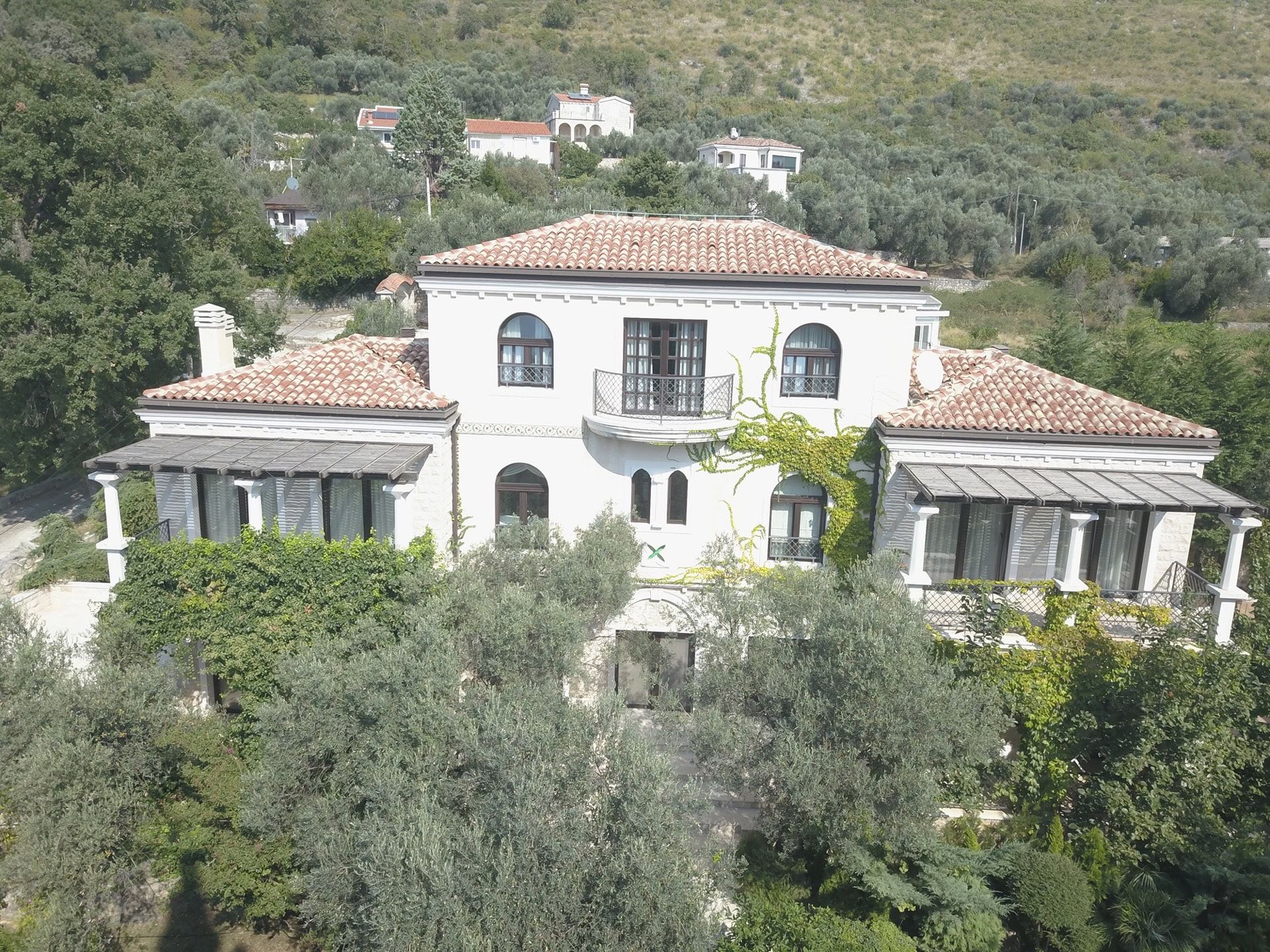 Villa à deux étages avec toit en tuiles et terrasses, entourée d’oliviers, Reževići, Monténégro.