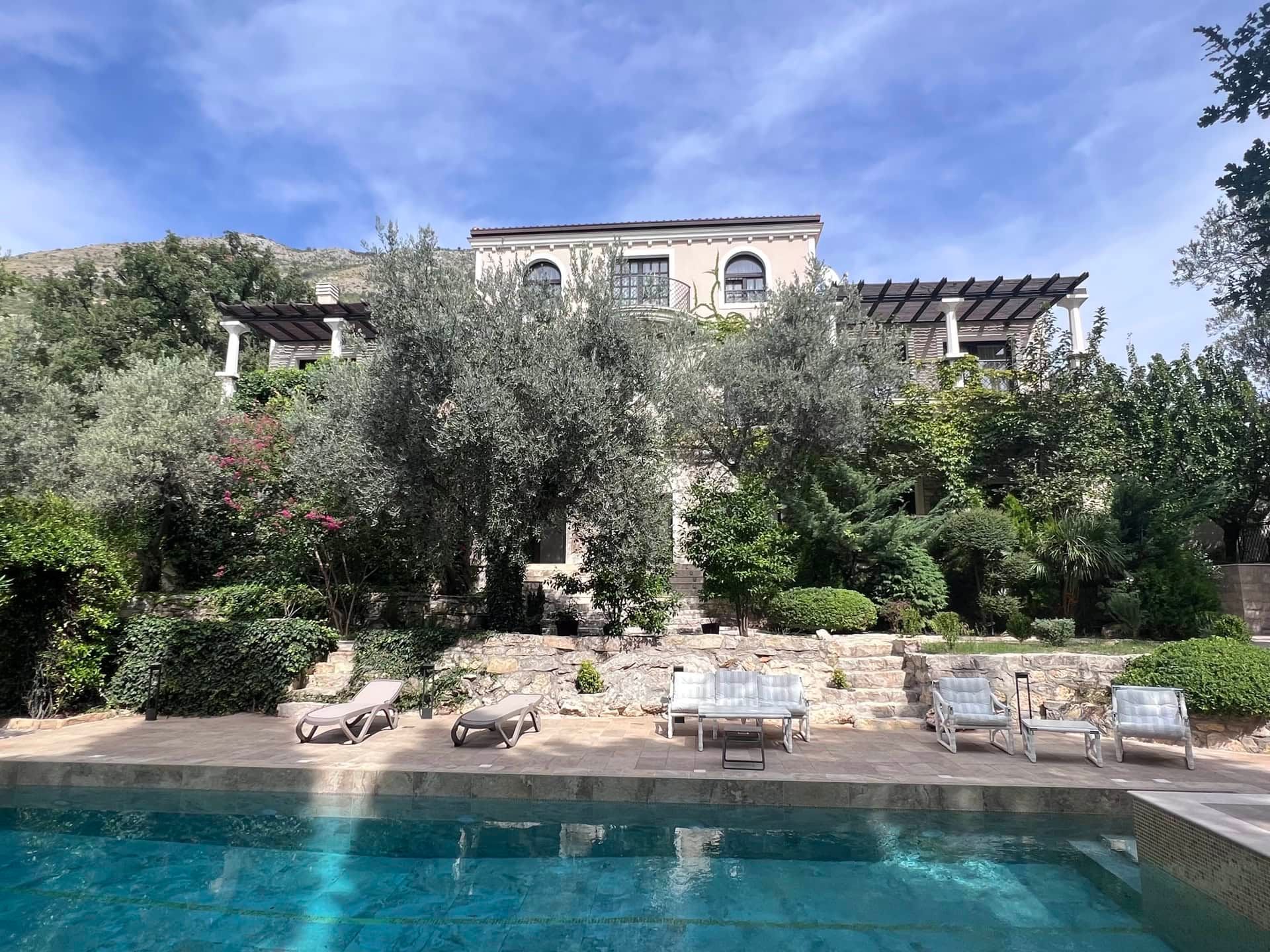 Villa de luxe avec piscine et espace détente à Reževići, Monténégro : vue sur la façade, le jardin et la terrasse avec transats.