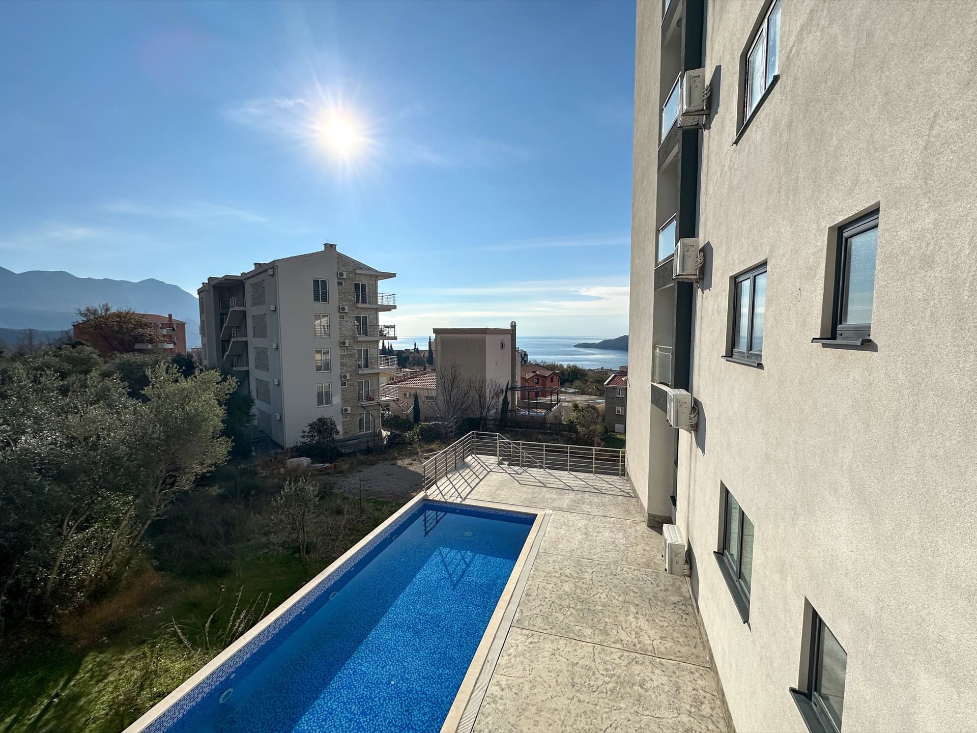 Offener Pool an der Wohnanlage in Bečići, Montenegro, mit Panoramablick auf das Meer und die Berge.