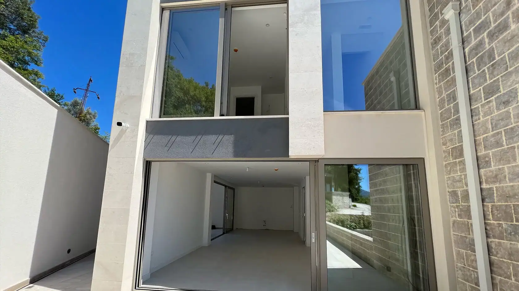 Moderne Villa mit Panoramafenstern und Steinverkleidung der Fassade in Tivat, Montenegro. Außenansicht der Wohnanlage.
